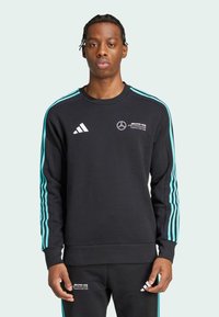 Sort sweatshirt med turkise striber, Adidas-logo og Mercedes-branding. Indeholder ribbet halsudskæring og manchetter. Glat tekstur.