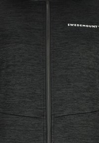 Black zip-up jacket with a textured fabric, featuring a vertical zipper and a small white logo on the upper left side.