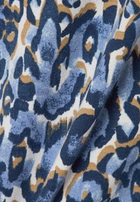 Strickstoff mit einem blauen und beigen abstrakten Leopardenmuster auf einem weißen Hintergrund, mit weicher Textur und unterschiedlichen Mustern im gesamten Stoff.