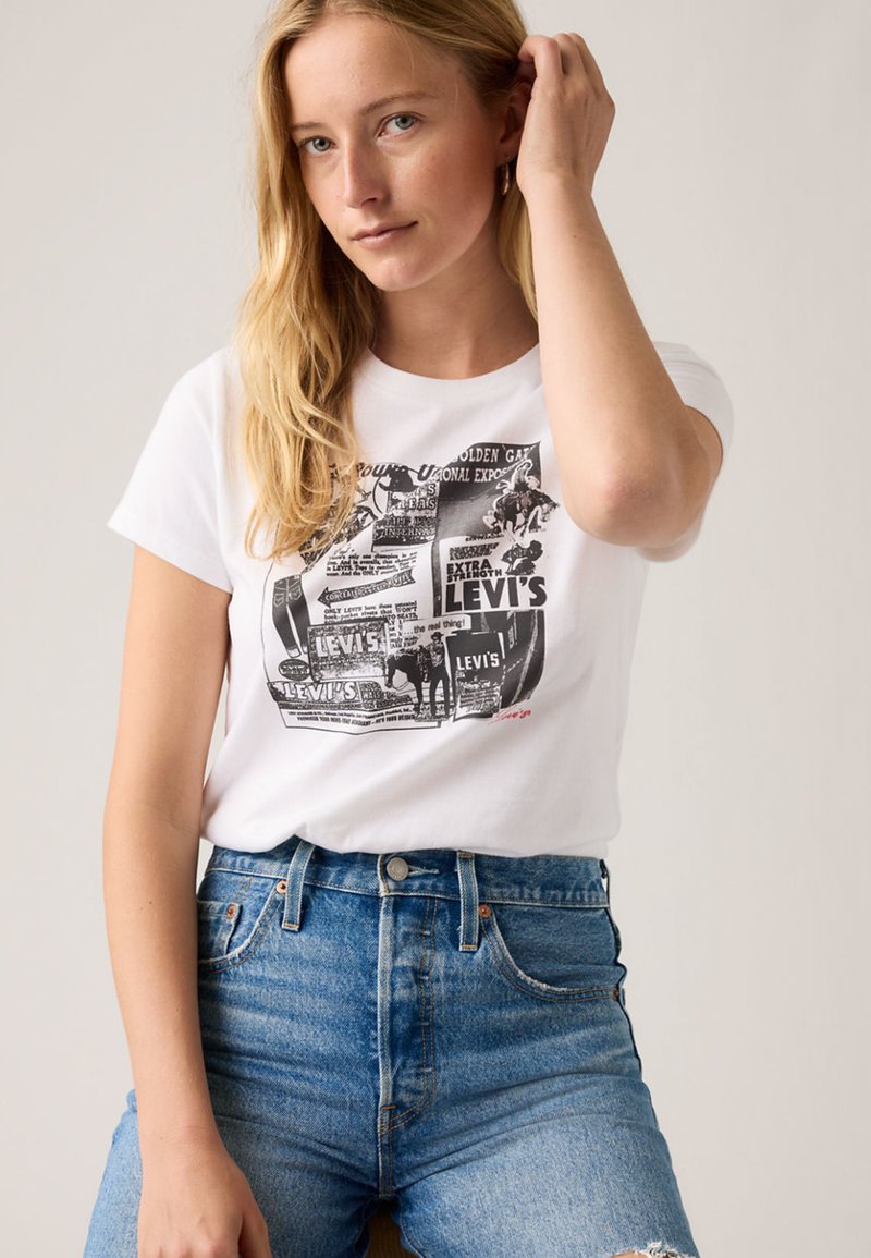 Λευκό βαμβακερό T-shirt με γραφική εκτύπωση με μαύρο κείμενο και εικόνες. Συνδυάζεται με σορτς από τζιν υψηλής μέσης σε μπλε απόχρωση.