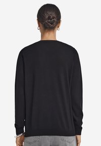 Svart långärmad tröja med rundad halsringning, tillverkad av mjukt material, med ribbade mudd och fåll, samt en slät yta.