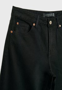 Svarta denimjeans med hög midja, utrustade med kopparnitar, knäppning och framfickor. Strukturen är jämn med lätt stretch.