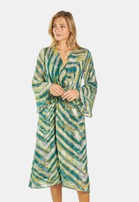 Blumengemusterter Kimono-Robenstil in grünen und beigen Tönen, mit weiten Ärmeln, einem tiefen V-Ausschnitt und einem Taillenzug, der eine verstellbare Passform ermöglicht.
