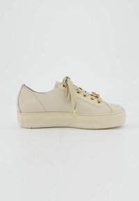 Béžové tenisky s hladkým koženým svrškem, zlatými žlábky a tkaničkami. Texturovaná gumová podrážka s jemnými drážkami pro lepší trakci.