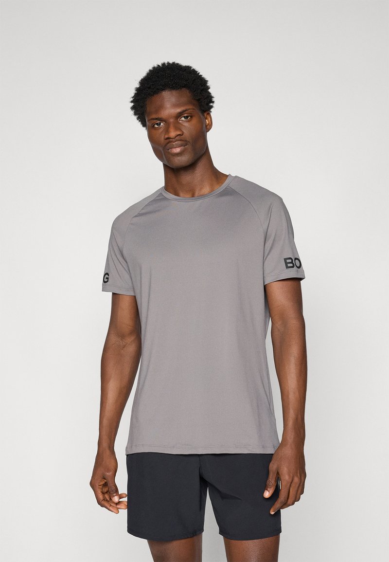 Graues kurzärmliges Sport-T-Shirt mit Rundhalsausschnitt und schwarzem Logo auf dem linken Ärmel. Glattes Material mit leichter Textur.