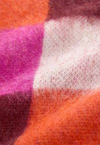 Bunt gestrickter Wollstoff mit einem karierten Muster in verschiedenen Schattierungen von Orange, Pink, Weiß und Braun; weiche Textur mit einem faserigen Aussehen.