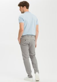 Jasnoniebieska koszulka polo z kontrastowym kołnierzykiem, zestawiona z jasnoszarymi chinosami. Stylizacja ma dopasowany krój i subtelny wzór teksturowy.