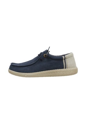 Zapato bajo informal con parte superior de tela azul marino, suela de goma beige texturizada, parche beige en el talón y cordones negros con ojetes amarillos.