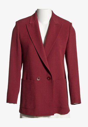 Veste croisée rouge foncé avec revers crantés et deux grandes poches avant, présentée sur un torse de mannequin blanc sur fond blanc.