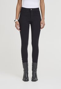 Černé slim džíny s vysokým pasem, vyrobené z pružného denimu. Mají přední zapínání na knoflík a zip a lichotivý střih.