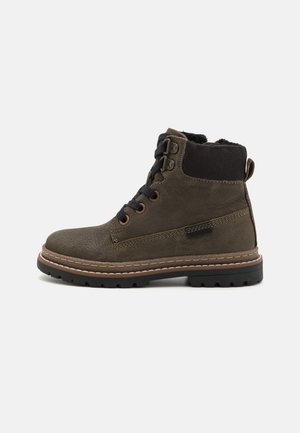 Bruine leren enkellaars met zwarte gewatteerde kraag, zwarte veters, metalen oogjes en dikke rubberen zool met beige stiksels.