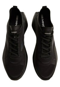 Chaussures de sport noires avec tige en mesh, design épuré, accents texturés et lacets en tissu. Style minimaliste avec un logo sur la semelle intérieure.