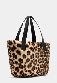 Tote bag met luipaardprint, gemaakt van een zachte, fuzzy textuur en voorzien van zwarte leren handvatten. De tas heeft een rechthoekige vorm en een opvallend gevlekt patroon.