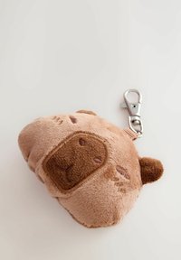 Small soft plush keychain shaped like a bear’s face with light brown and dark brown fabric and a silver metal clasp.