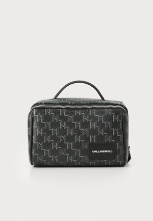 Black cosmetic case with textured exterior, featuring a geometric pattern, top handle, and zip closure. Includes logo patch on the front.