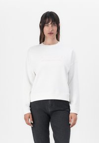 Fehér pulóver puha anyagból, kerek nyakkal és bordás mandzsettával. Az elején pasztell színű betűkkel található a "BARBOUR INTERNATIONAL" felirat.