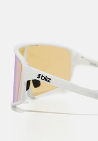 Lunettes de soleil blanches avec un design enveloppant, verres teintés orange et détail de logo noir sur la branche. Accents texturés sur les plaquettes de nez.