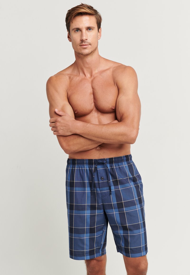 Blå rutiga shorts gjorda av lättviktsmaterial, med resårmidja, snörning och en enkel knappstängning fram.