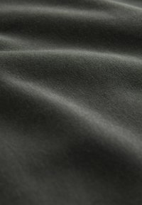 Sort stof, blød tekstur, med synlige folder og varierende lysreflekser, der viser en glat, mat finish.