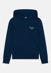 Marineblå hoodie i mjukt material, med en framficka, ribbade ärmslut, och en vit "Calvin Klein Jeans" logo på bröstet.