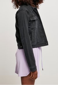 Černá džínová bunda s klasickým designem, vybavená předními kapsami, knoflíkovým zapínáním a střední délkou. Měkká textura s jemným vyblednutím.