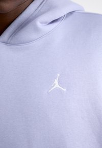 Felpa lilla realizzata in morbido tessuto, con il logo Jumpman bianco sul petto, dotata di cappuccio e dettagli cuciti attorno al collo.