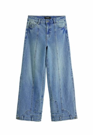 Jeans bleu clair à jambe large en denim, avec une taille haute, des détails de coutures distincts et des accents en forme de patch sur les poches arrière.