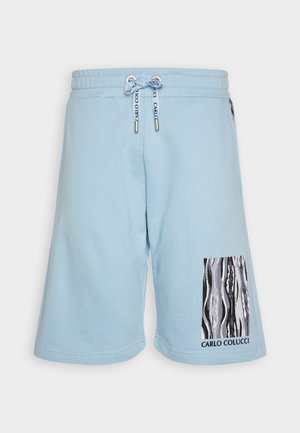 Light blue cotton shorts with an elastic waistband and drawstring. Features a printed patch in black and white on the right leg.