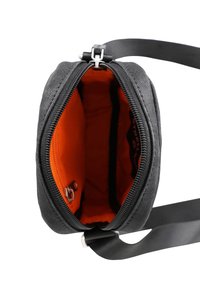 Svart tyg crossbody-väska med dragkedjestängning. Insidan har en ljus orange foder och en liten ficka, samt en justerbar rem.
