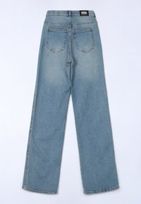 Jean bleu clair à coupe droite avec poches arrière et une étiquette de marque noire sur la ceinture, vu de dos.