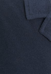 Marina bomullshanddukar med en texturerad yta, som har en tät väv och rena kanter. Tyget framstår som mjukt och absorberande.