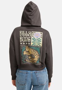 Sudadera con capucha en gris oscuro que presenta un diseño gráfico colorido en la parte posterior, que incluye un tigre, flores y estrellas. Material de algodón, estilo corto.
