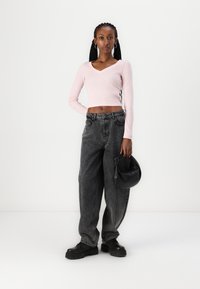 Heled roosa ribaga lühike topp v-dekoltee jaotusega. Kõrge vöökohaga mustad teksapüksid, laiad sääred. Must ümmargune käekott ja massiivsed mustad kingad.