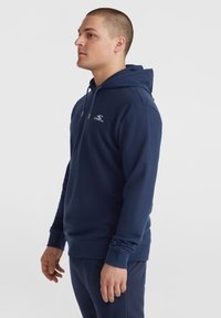 Hoodie bleu marine en tissu doux, avec une poche kangourou à l'avant, une capuche avec cordon ajustable et un logo sur la poitrine.