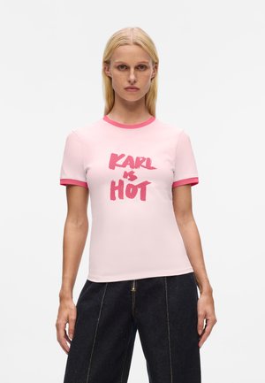T-shirt ajustée rose à manches courtes, avec un col en rib de couleur rose contrastante et le texte "KARL IS HOT" en gras, en style peinture au pinceau.