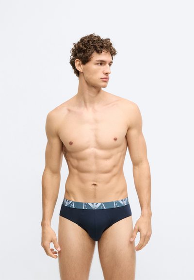 Cueca azul-marinho com cintura elástica texturizada e logótipo em cores contrastantes. Tecido suave, corte contornado e design de cobertura mínima.