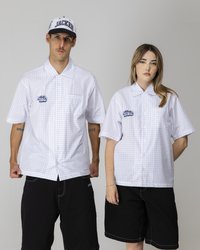To modeller står side om side, iført overdimensjonerte kortermede hvite rutete skjorter og svarte shorts, og viser en avslappet gatekulturstil.