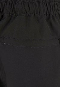 Sorte shorts med elastisk talje, der har en enkelt baglomme og fladsyede kanter, lavet af et glat, let stof.