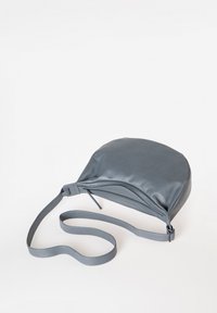 Grijze leren crossbody tas met een afgeronde vorm, gladde textuur, verstelbare schouderband en bovenste ritssluiting. Minimalistisch ontwerp zonder extra accenten.