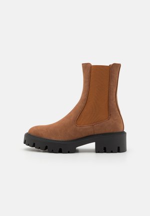 Bottines Chelsea marron avec des panneaux latéraux en élastique, en simili cuir texturé et une épaisse semelle en caoutchouc noir dotée d'un motif de semelle profond.