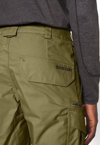 Olivengrønne cargobukser med en tekstureret finish, der har en baglomme med "BURTON"-mærke og synlig detalje på sidelommen.