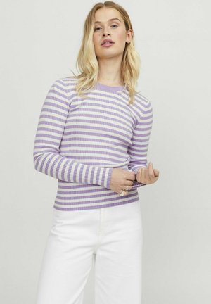 Top de manga larga a rayas moradas y blancas con escote redondo y silueta ajustada. El modelo lleva pantalones blancos.