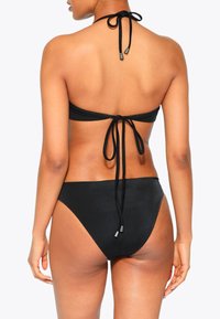 Zwarte bikini met een halternekdesign, voorzien van een gestrikte rug en een gladde, minimalistische textuur. Hoge uitsnijding aan de onderkant accentueert de taille.