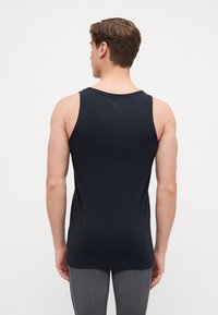Schwarzes Tanktop aus einem glatten Material mit Rundhalsausschnitt und breiten Trägern. Es schmiegt sich eng an den Körper und hebt das Rückendesign hervor.