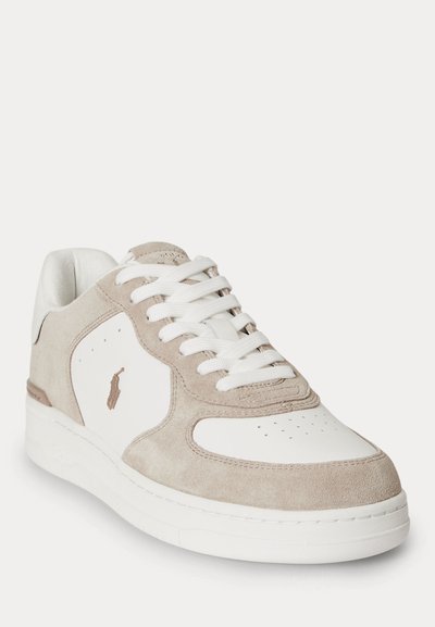 Beigen värinen matalakärkinen tennari mokkaa ja valkoista nahkaa, joissa valkoiset nauhat ja pieni kirjailtu logo sivussa.