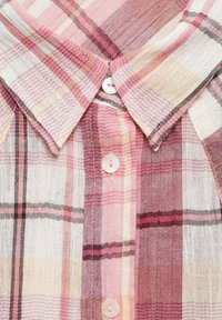 Button-up shirt in a lightweight, woven fabric featuring red, pink, and cream check patterns. Includes a pointed collar and pearl-like buttons.