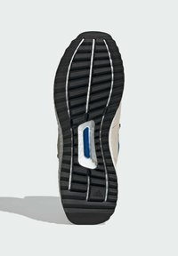 Svart gummisula med djupa spår, vit mellansula och ett blått detaljfönster. Texturerad yta och akcentueringsspår finns närvarande.