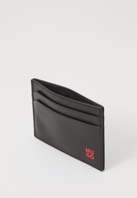 Portofel de carduri din piele neagră, având multiple sloturi pentru carduri și un mic logo roșu. Textură netedă cu cusături precise și design minimalist.