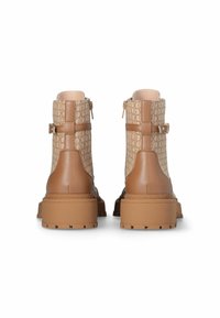 Bottines brunes en tissu beige texturé et cuir, avec des fermetures éclair sur les côtés et des semelles en caoutchouc épaisses.