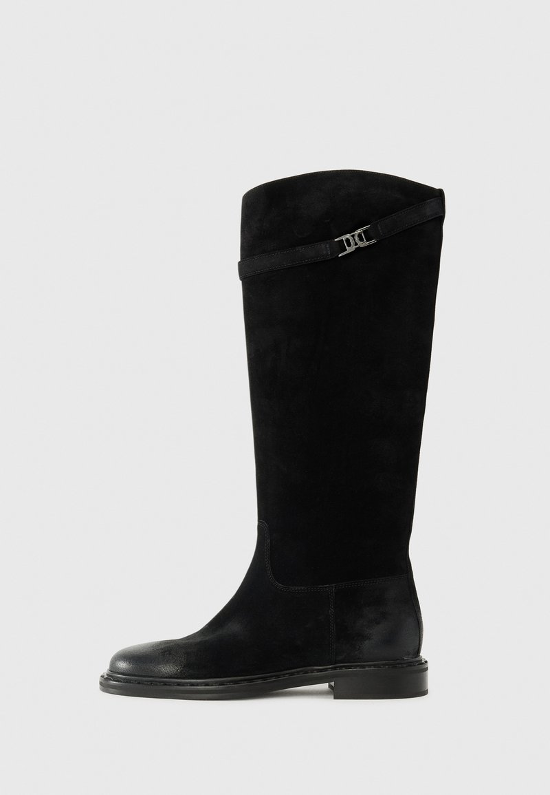 Botas de ante negras hasta la rodilla con punta redonda, tacón plano y una correa decorativa con una hebilla plateada en la parte superior.